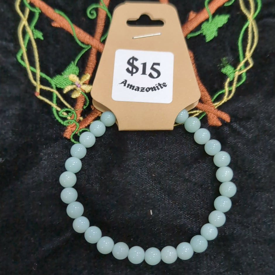 Green beaded bracelet on a black surface with a price tag of $15.