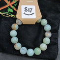 Green beaded bracelet on a cardboard holder with 'Amazon' label on a dark background