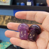 Hand holding two purple stones with a store display in the background