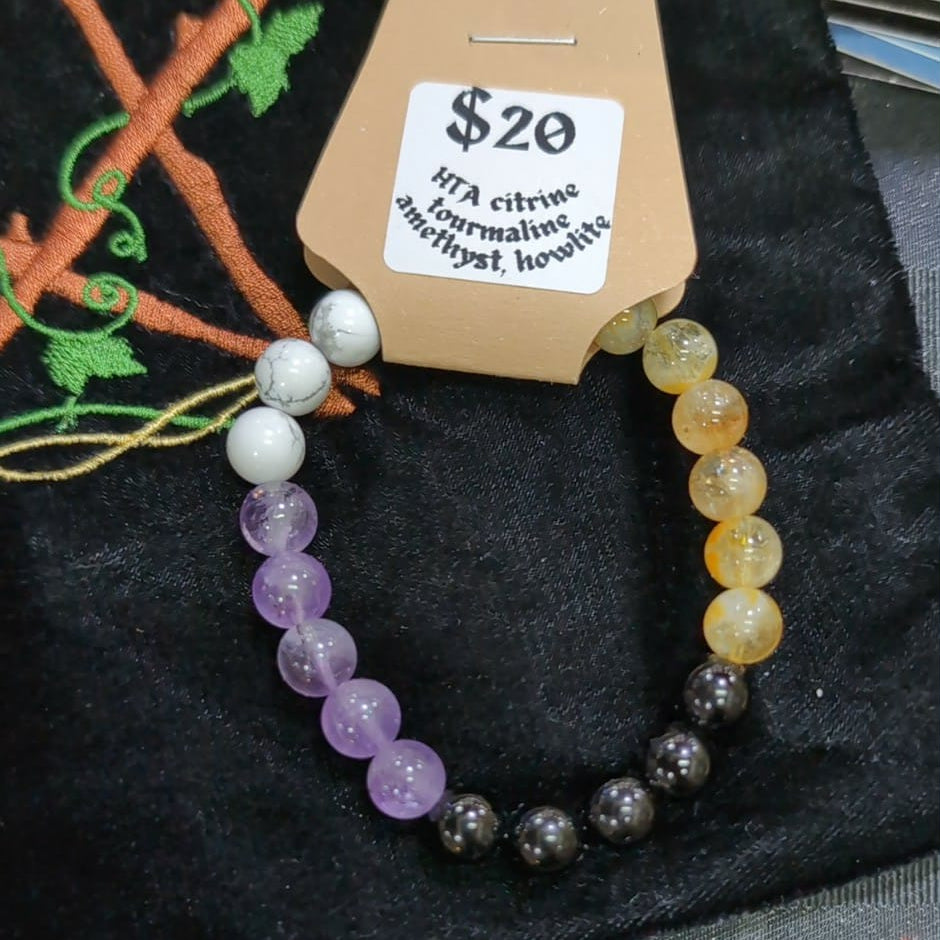 Colorful beaded bracelet on a cardboard holder with a price tag, on a dark fabric background.