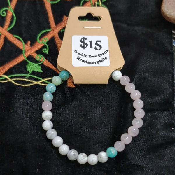 Beaded bracelet on a cardboard holder with a price tag against a dark embroidered background