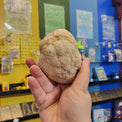 Hand holding a rock in front of a colorful display with toys and games.
