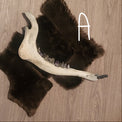 A taxidermy-style moose jaw displayed on dark brown fur pelts laid on a light wood background.