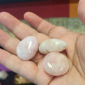 Hand holding three pink stones with a blurred background