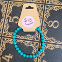 Turquoise beaded bracelet with a price tag on a decorative black and gold book