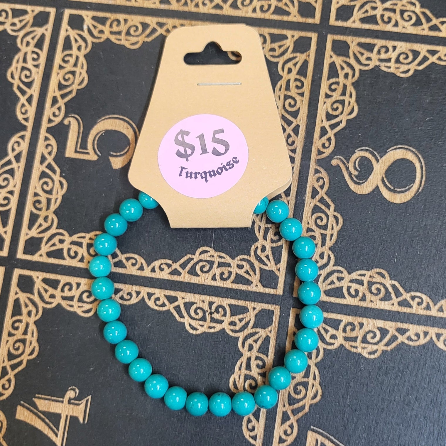 Turquoise beaded bracelet with a price tag on a decorative black and gold book
