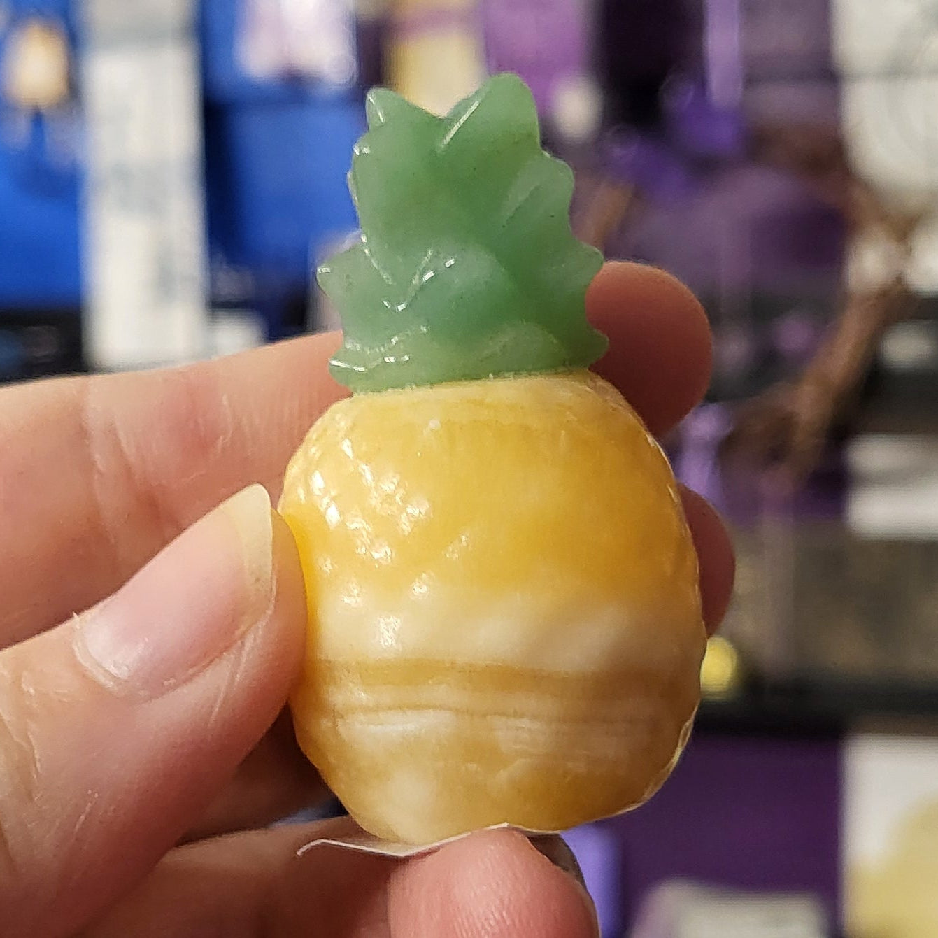 Hand holding a small fruit with a leaf on a blurred background